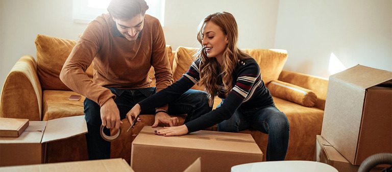 A couple packing boxes to move to downsize to a new apartment