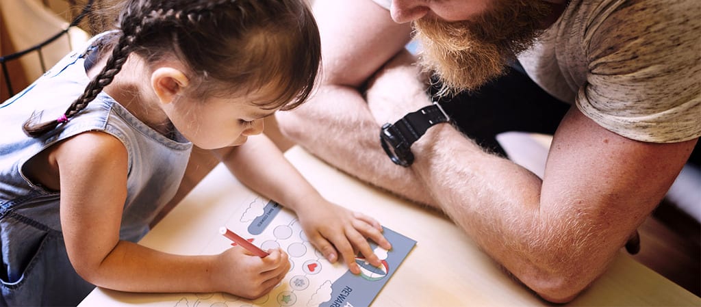 father helping daughter fill out chore chart