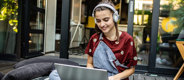 College student listening to music and typing on their laptop