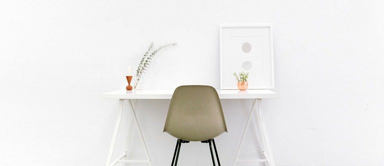 minimalist desk with white background and neutral color chair