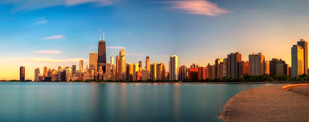 A panoramic view of the Chicago skyline from across the water at sunset.