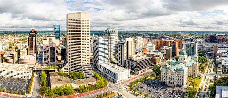 An aerial view of the city of Indianapolis on a bright cloudy day.