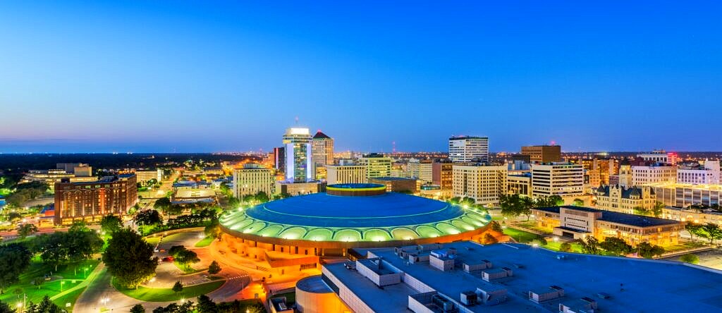 An aerial view of the city of Wichita at dusk with the city lights glowing.
