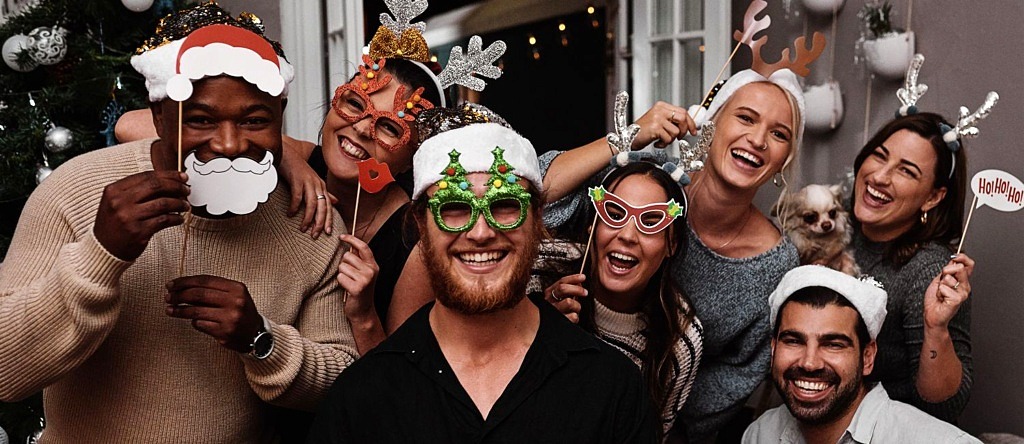 A group of friends wearing Christmas-themed photo booth accessories.