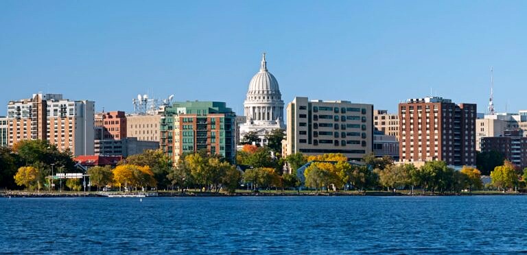 The Madison, WI skyline as seen from across one of the many lakes around the city on a clear blue sky day.